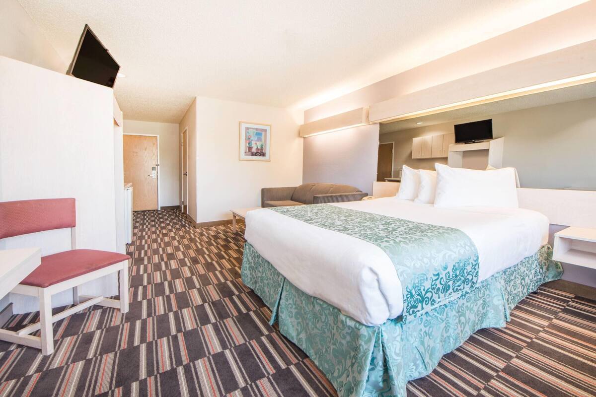A hotel room with a bed, a desk, a chair, a television, and a bathroom door.