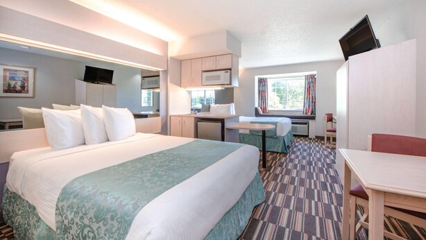 Una habitación de hotel con una cama, un escritorio, una silla, un televisor y una ventana.