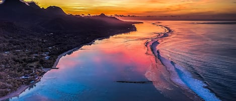 Un paisaje costero con playa y montañas durante el atardecer.