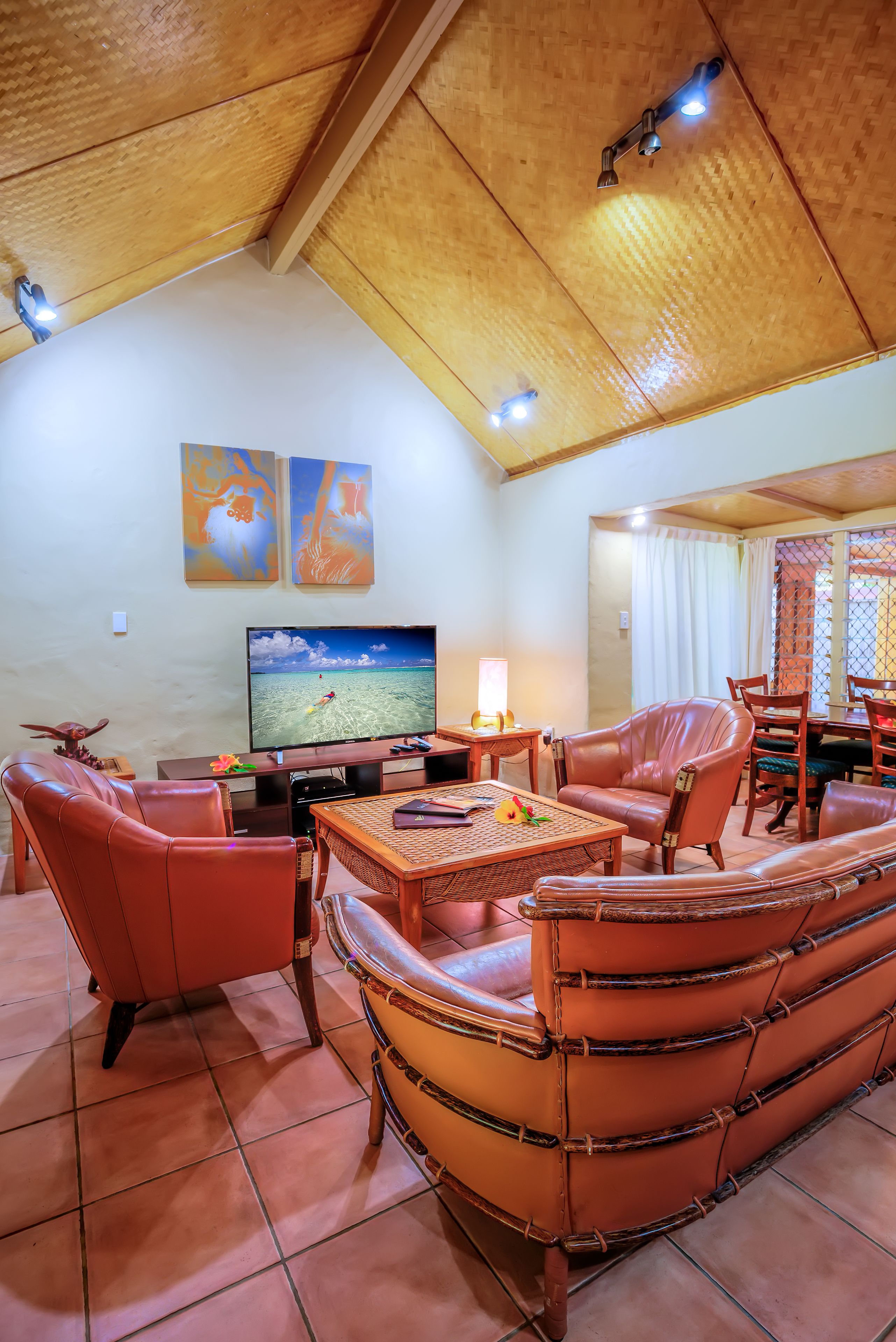 A living room with a television, leather furniture, and a wooden ceiling.