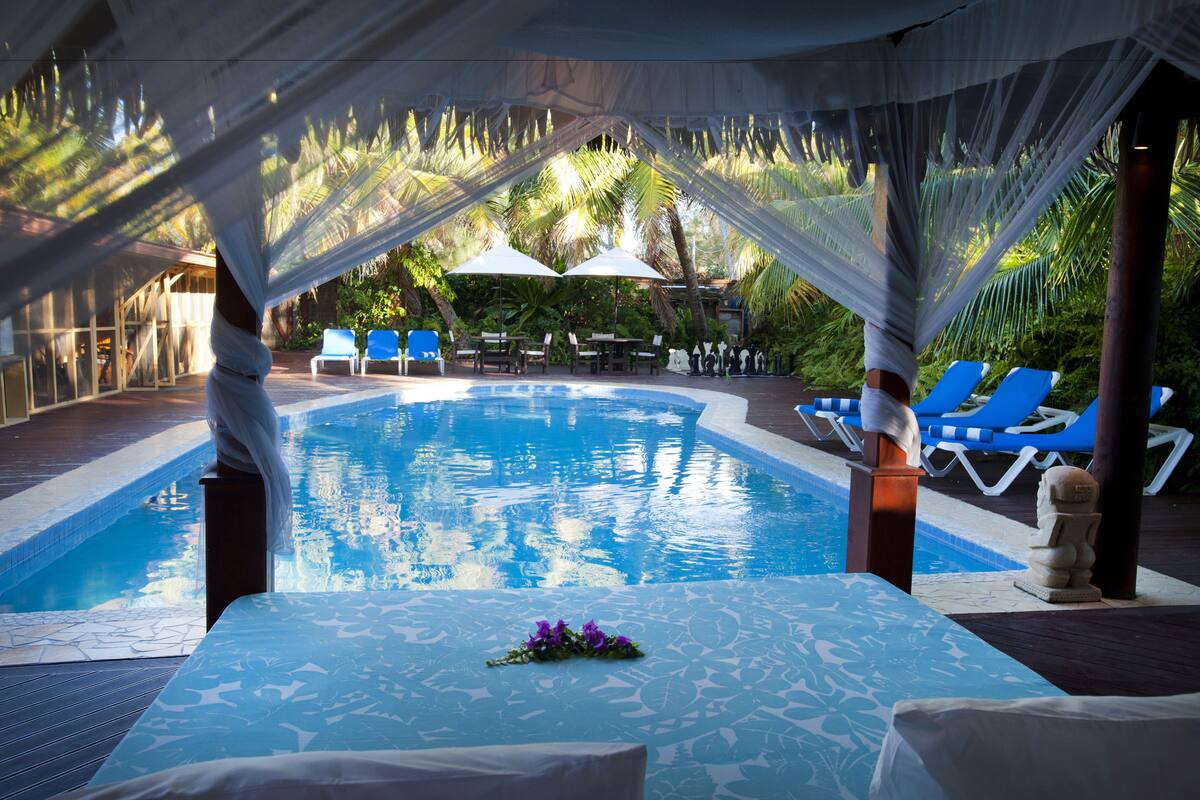A pool area with a clear view of the water, lounge chairs, and a table with a flower arrangement.