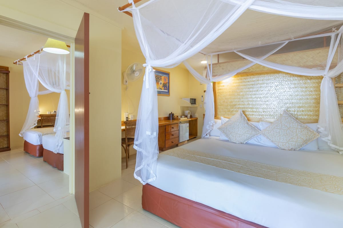 A bedroom with a bed under a canopy, a desk with a chair, and a bedside table.