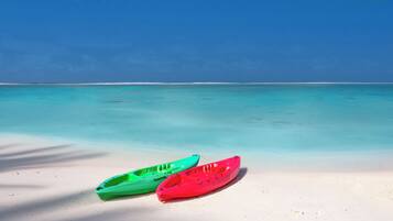Two kayaks on a sandy beach with clear turquoise water and a blue sky.
