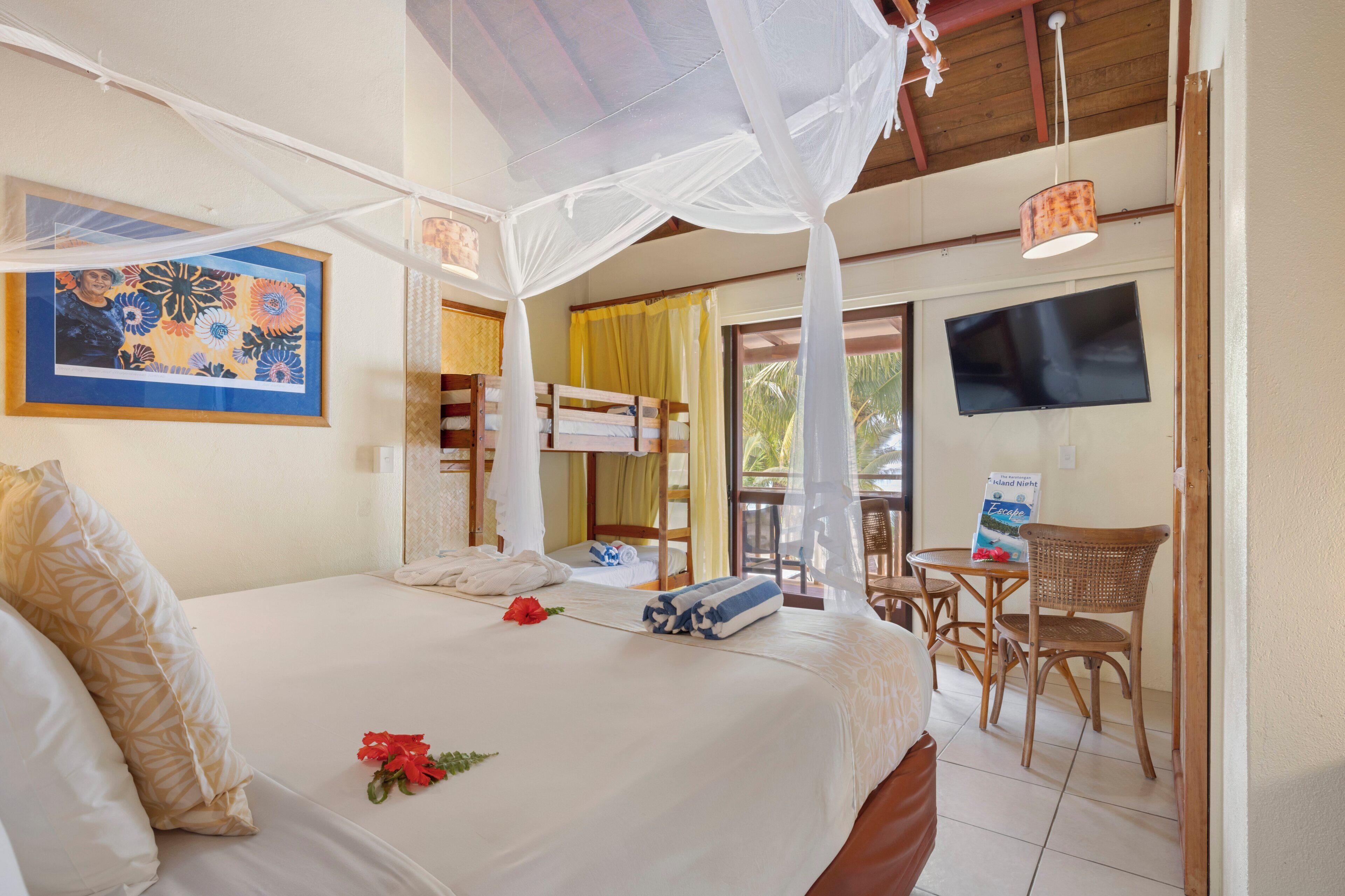 Una habitación de hotel con cama, televisión, balcón y zona de comedor.