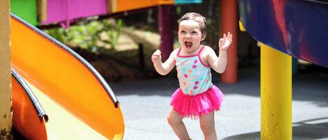 A child playing on a playground with a slide and colorful structures.