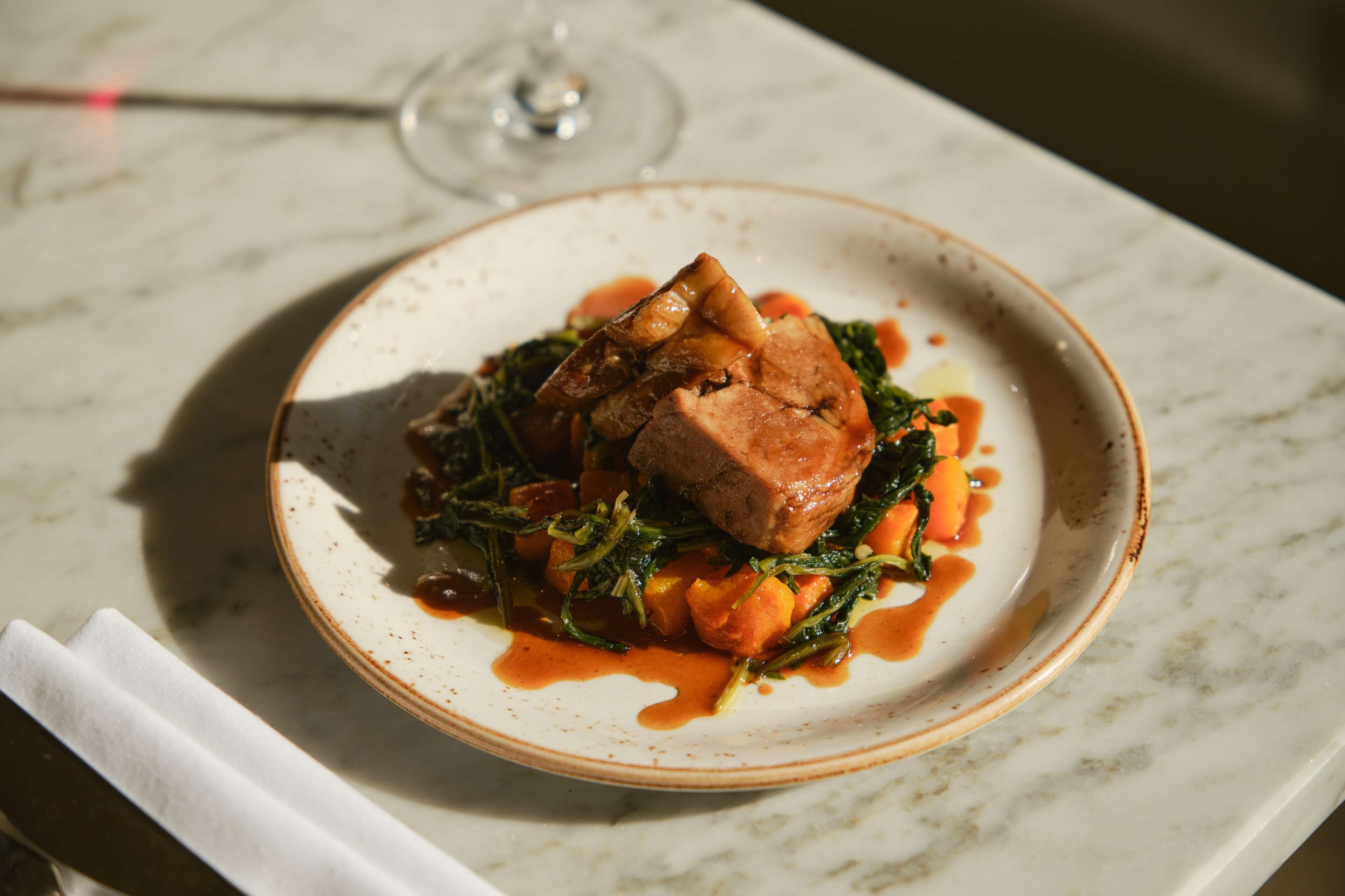 A plate of food with a glass of wine on a marble table.