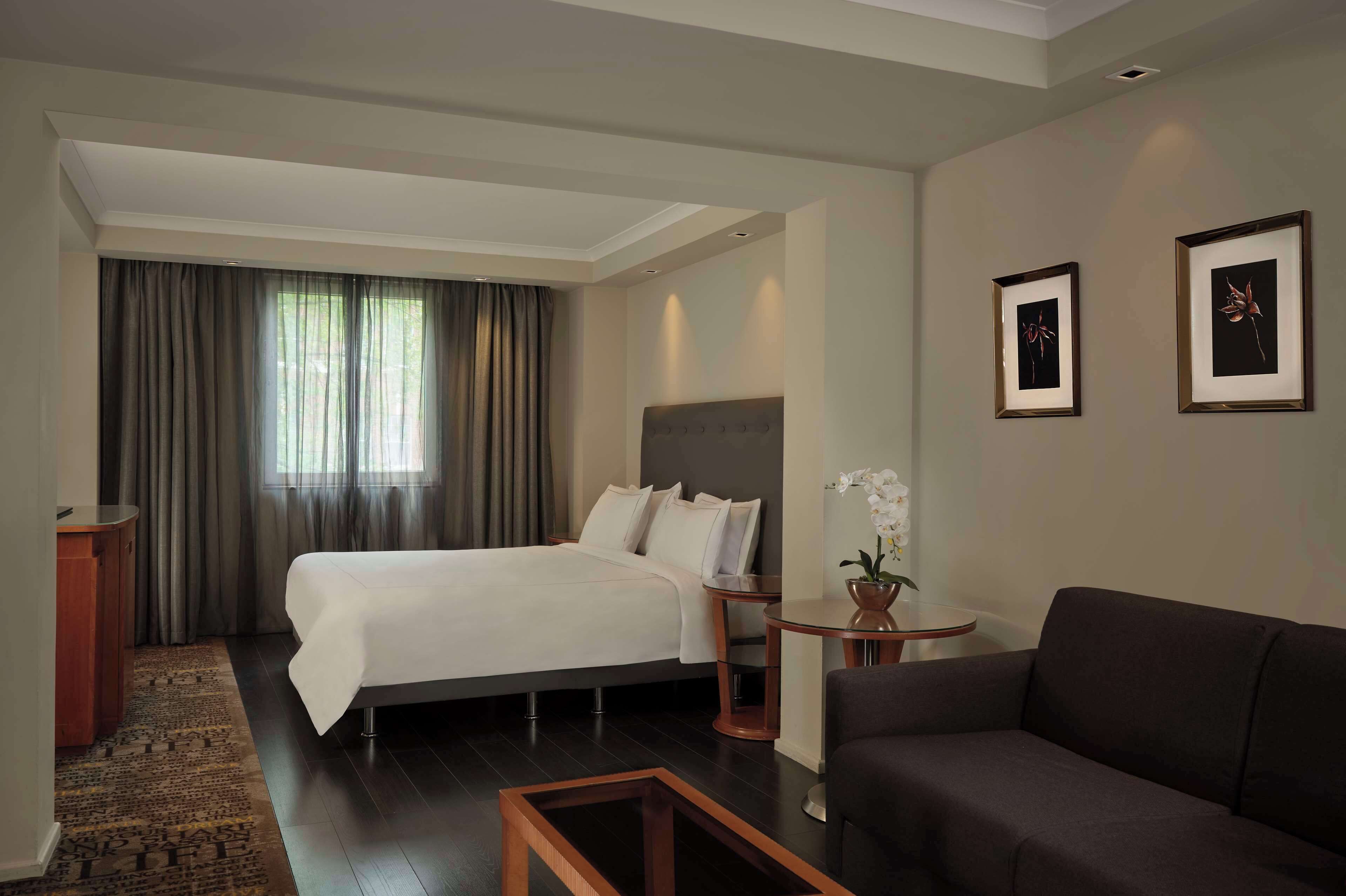 Ein Hotelzimmer mit Bett, Sofa, kleinem Tisch und Schreibtisch.