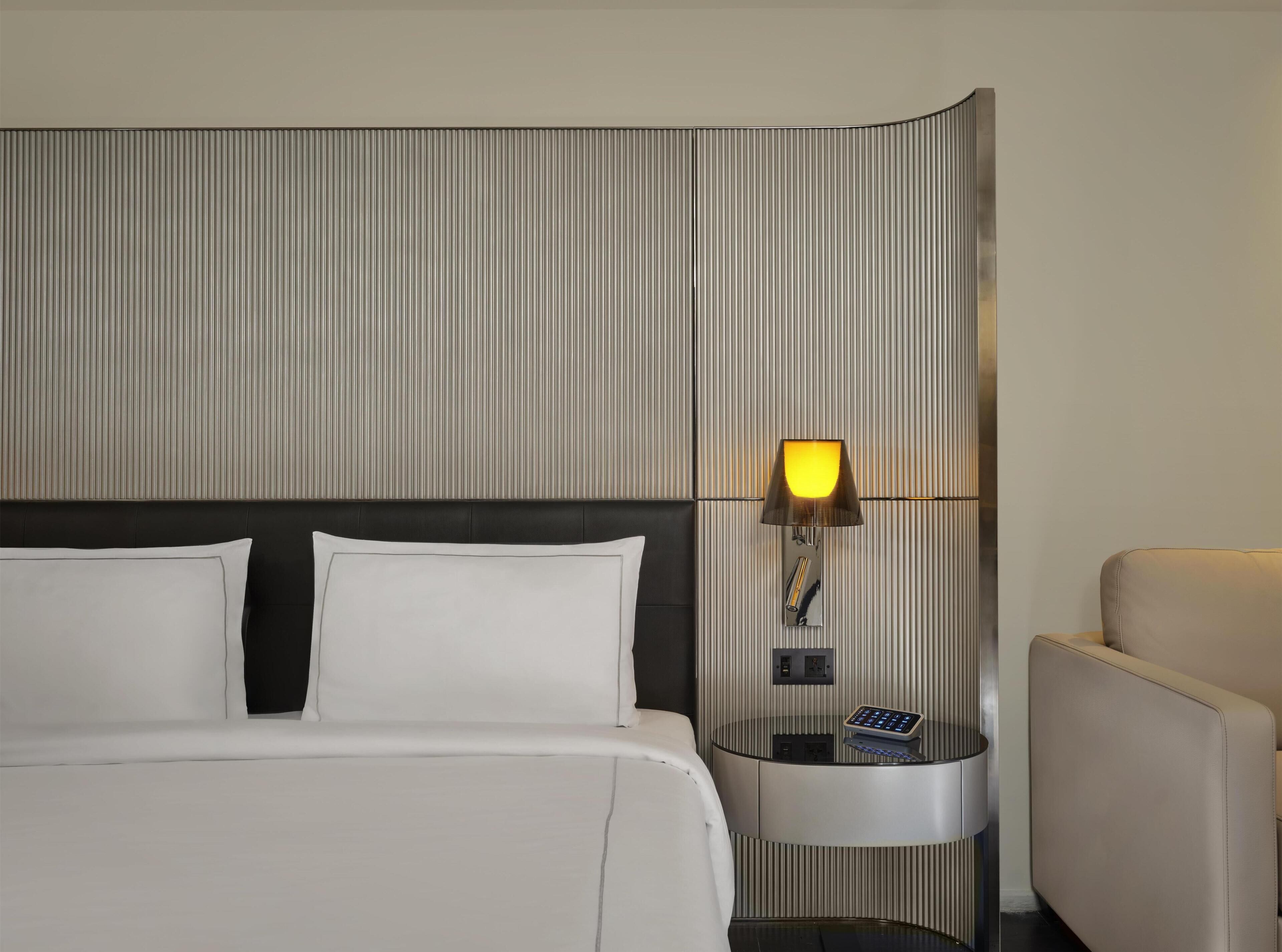 Une chambre d’hôtel avec un lit, une table de chevet, une lampe et une chaise.