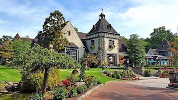 A historic building with a prominent tower, surrounded by well-maintained gardens and a paved walkway.