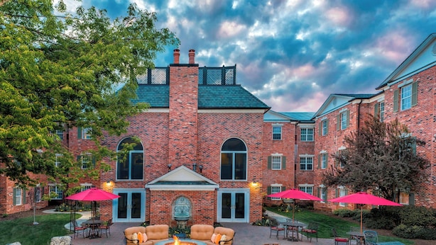 A brick building with a courtyard patio featuring outdoor seating and a fire pit.
