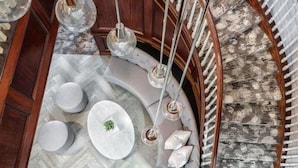A curved staircase with a round table and seating area, pendant lighting, and patterned wall.