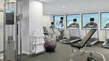 A gym with exercise equipment, a wall-mounted rack of towels, and a large exercise ball.