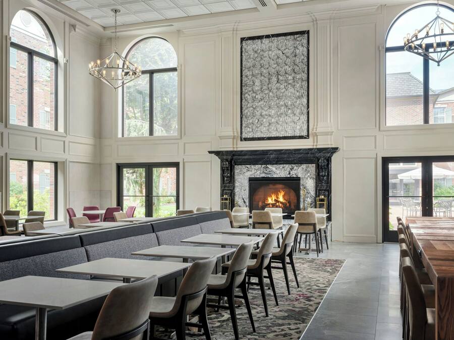 A spacious dining area with high ceilings, large windows, and a fireplace.