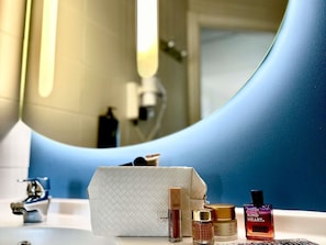 A bathroom vanity with a mirror, sink, and toiletries including a bottle of perfume, a jar of cream, and a box. - ibis budget Madrid Alcorcon Móstoles (Alcorcon)