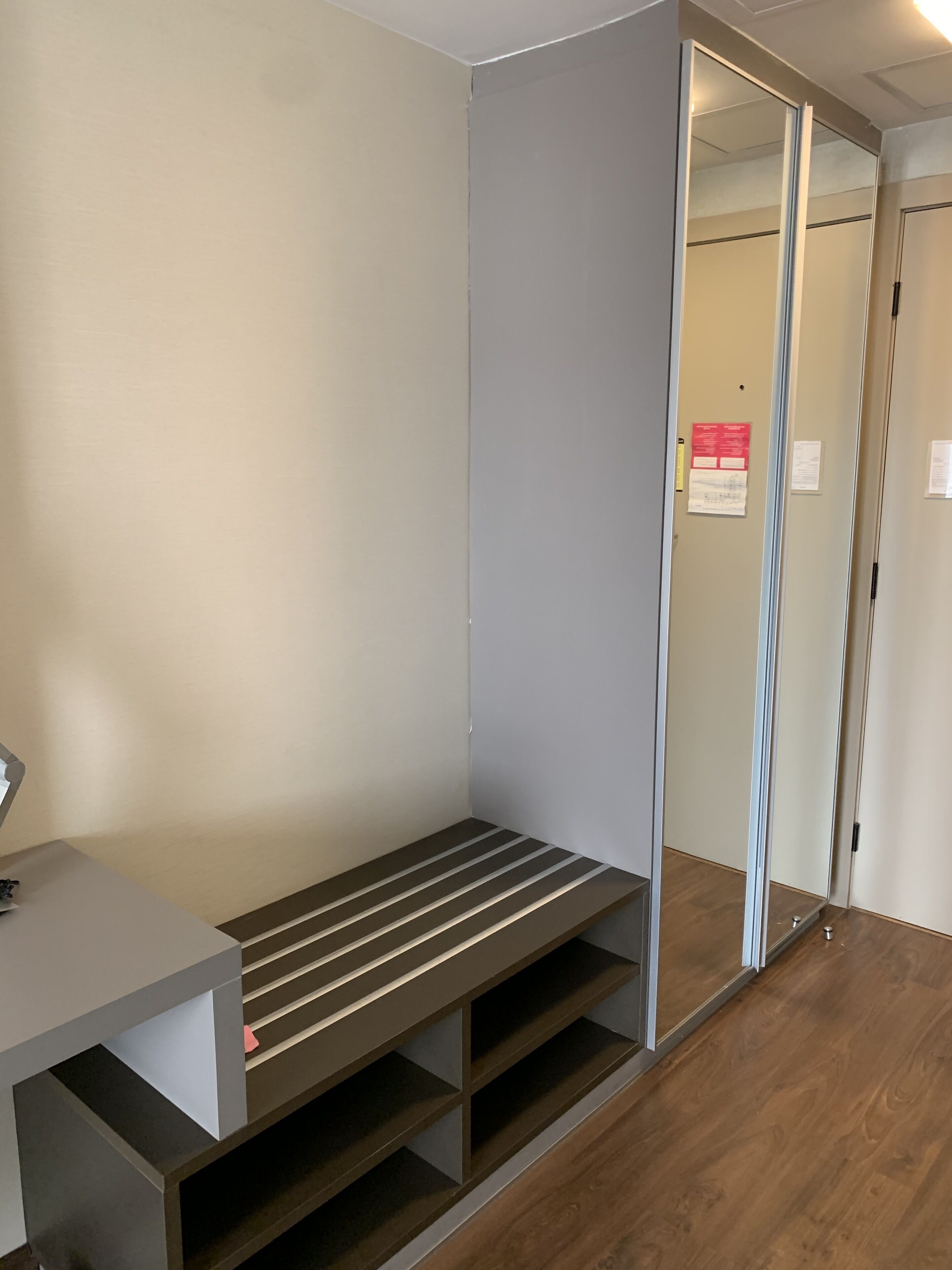 A room with a bench, a desk, and a sliding door.