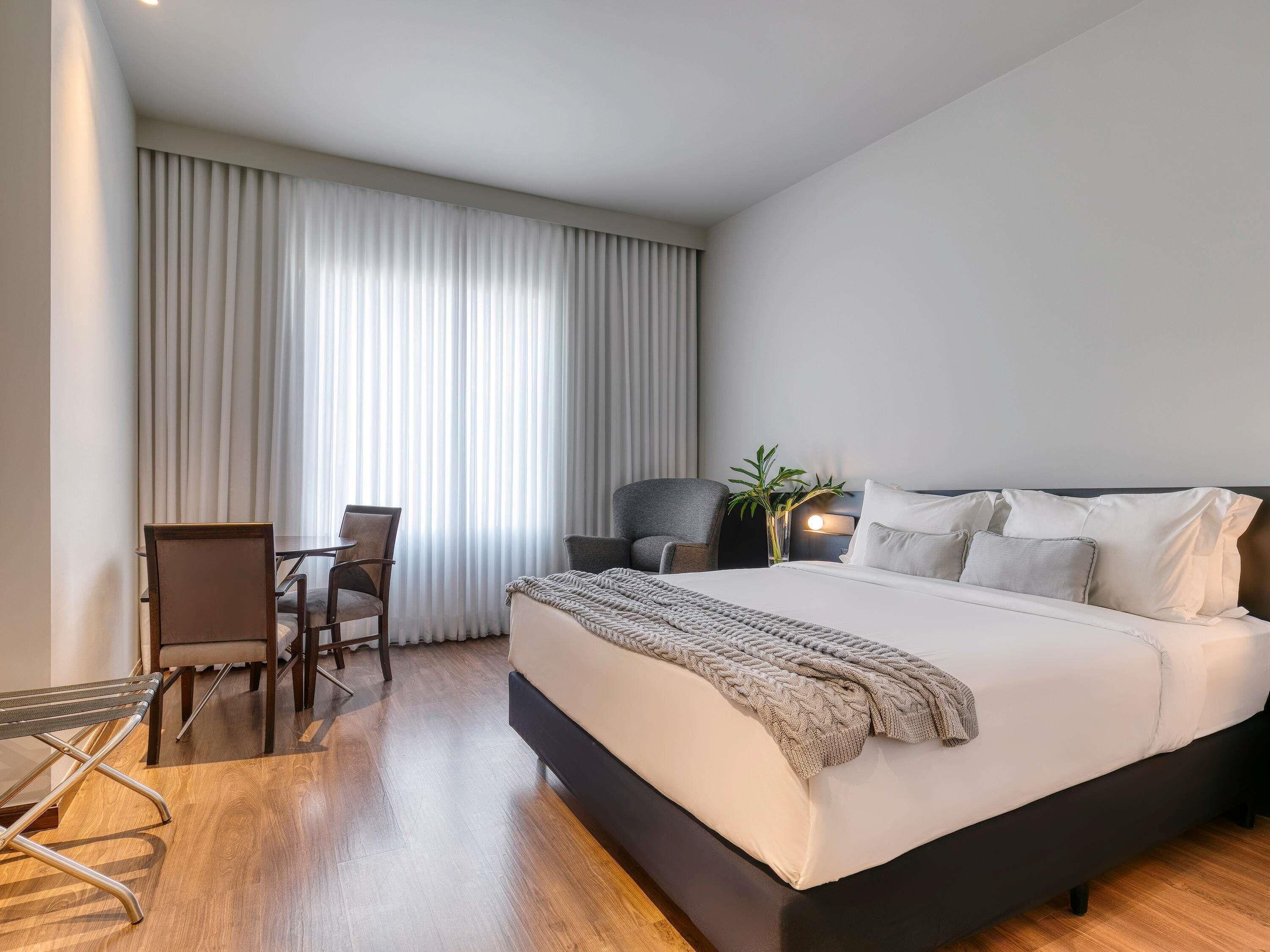 Una habitación de hotel moderna con una cama grande, un escritorio y una silla.