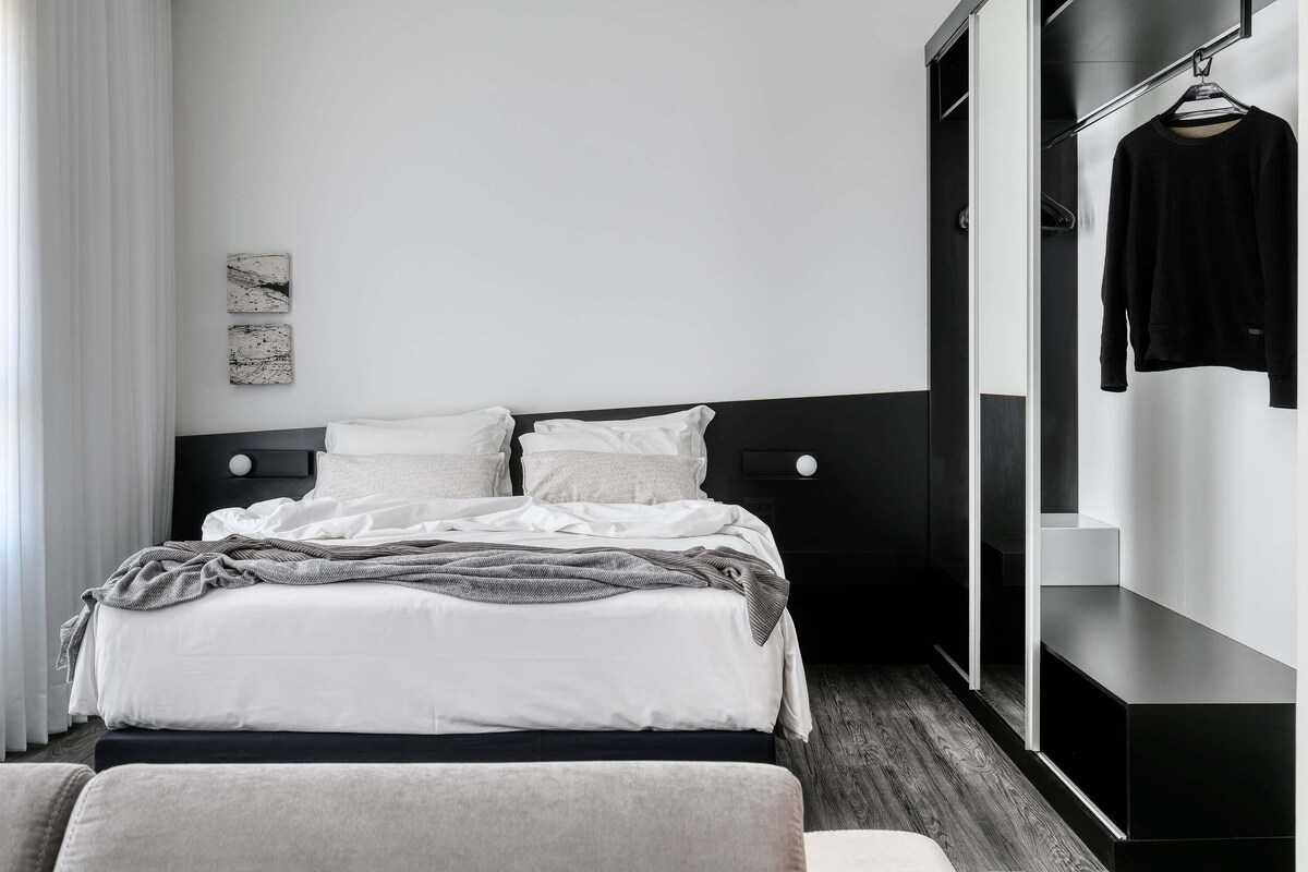 A modern hotel room with a bed, a wardrobe, and a hanging garment rack.