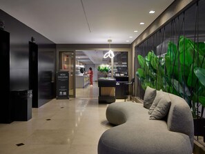 Eine moderne Hotelhalle mit einer Rezeption, einer Sitzgelegenheit mit individuellem Design und einer großen, begrünten Wand.