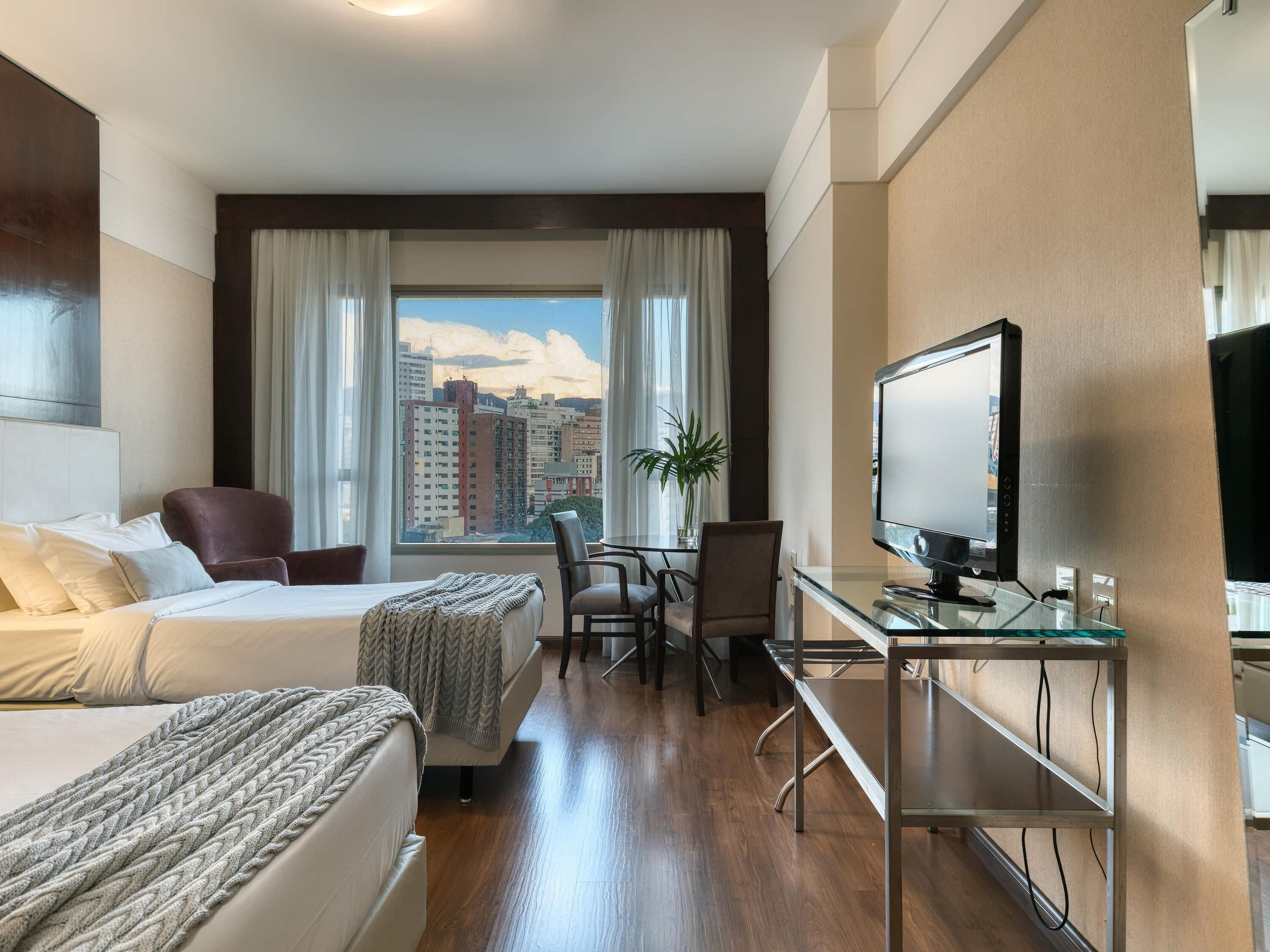 Una habitación de hotel con una cama, un escritorio, una silla y un televisor.