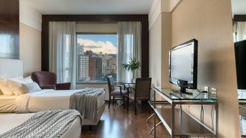 A hotel room with a bed, a desk, a chair, and a television.