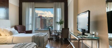 Una habitación de hotel con una cama, un escritorio, una silla y un televisor.