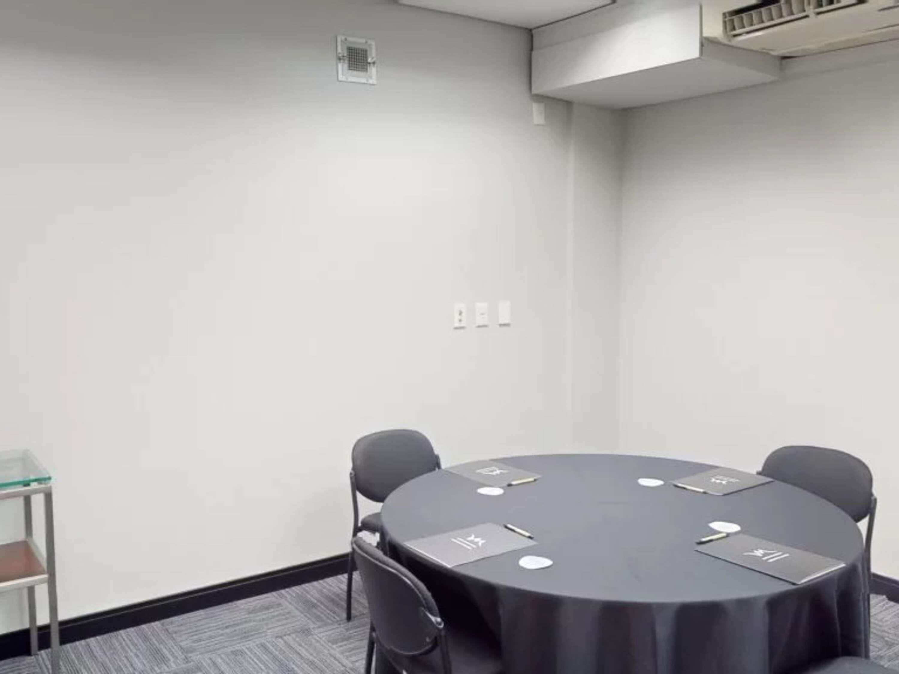 A conference room with a round table, chairs, and a glass partition.