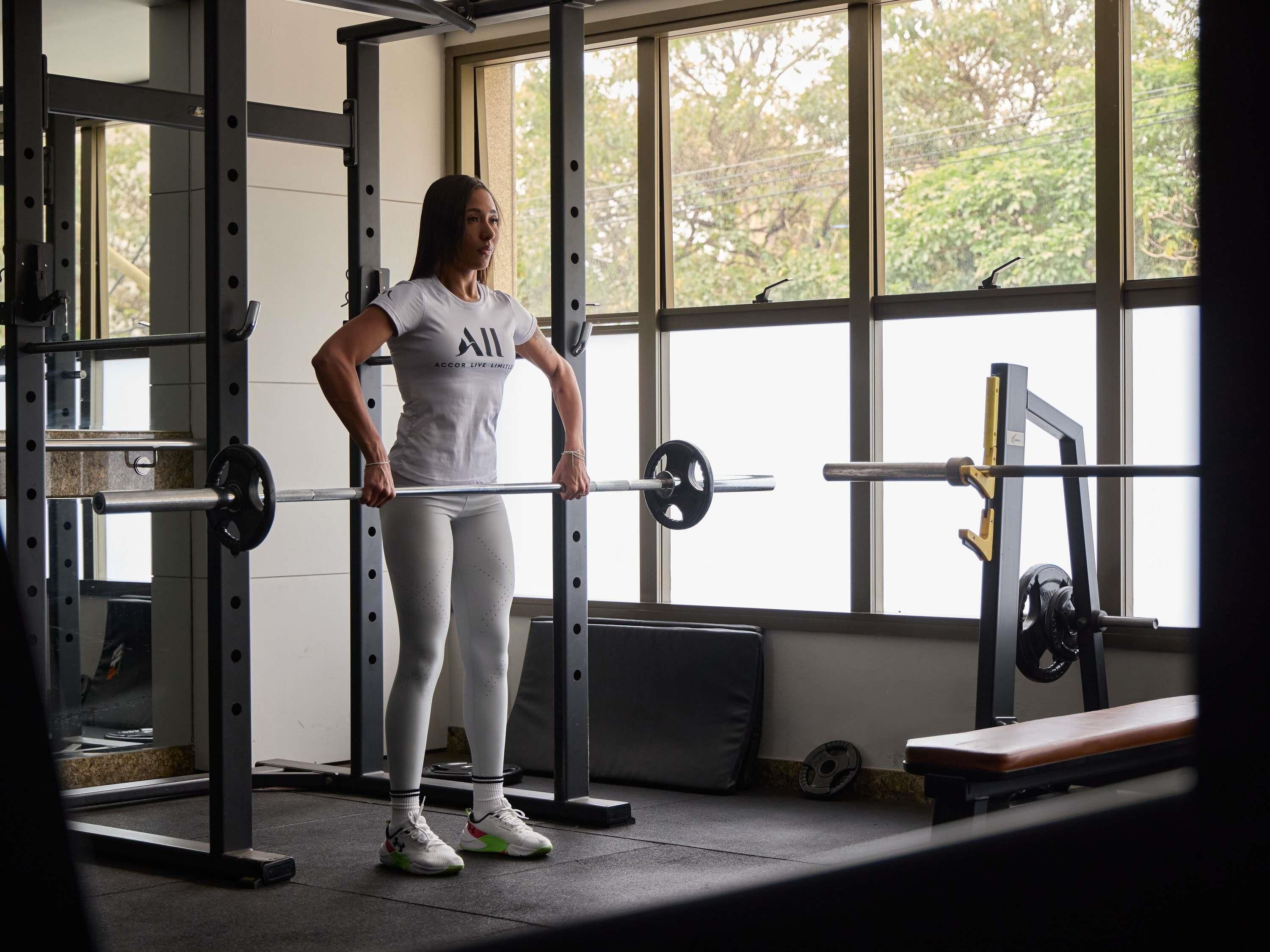 A gym with a barbell rack, weights, and a bench.