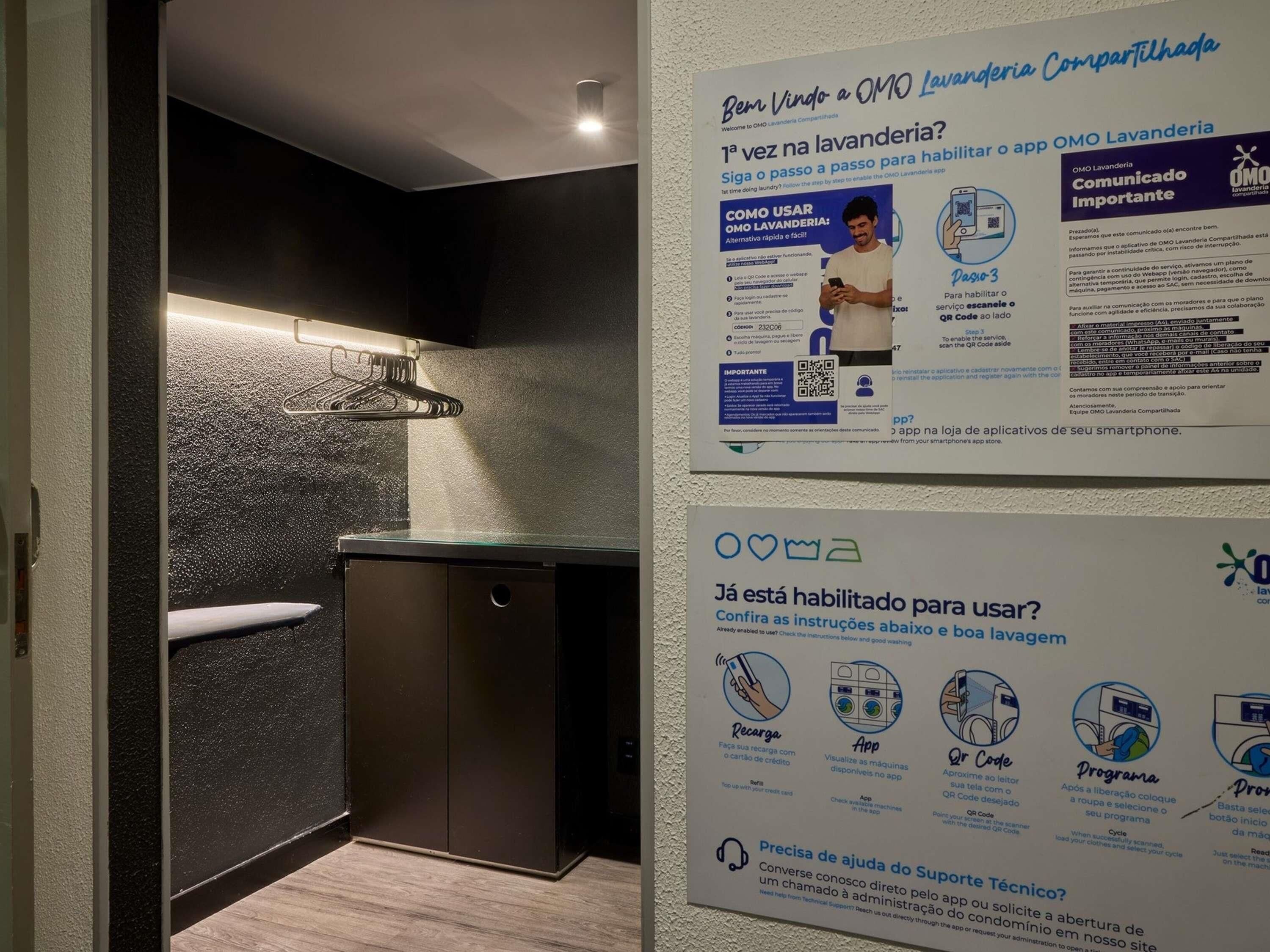 A modern bathroom with a built-in washing machine, a towel rack, and instructional posters on the wall.