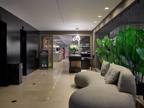 Un moderno vestíbulo de hotel con una recepción, una zona de estar de diseño único y una amplia pared cubierta de plantas verdes.