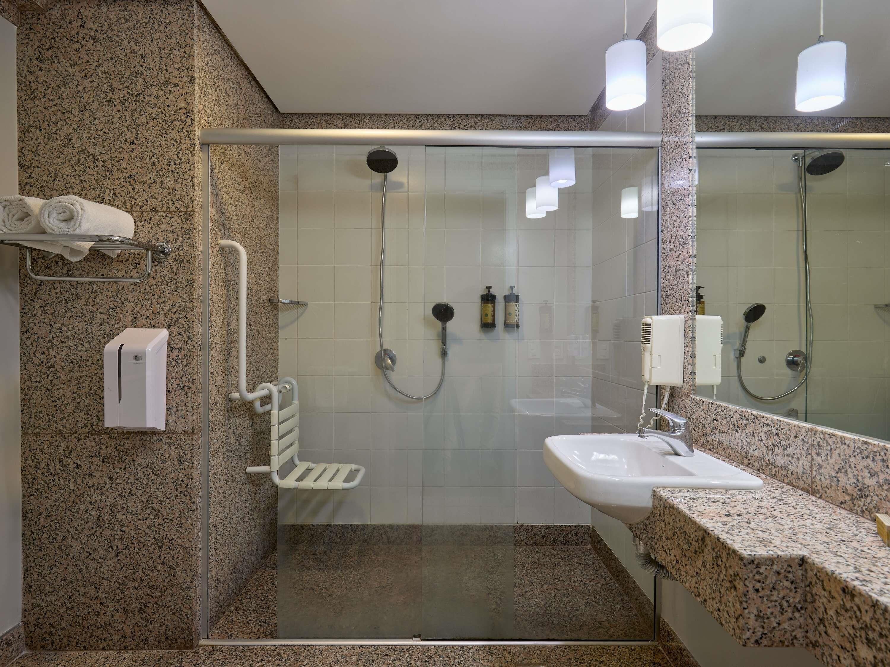 A modern bathroom with a glass-enclosed shower, a sink, and a towel rack.