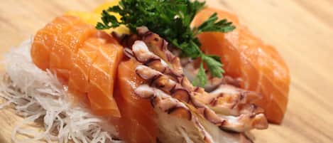 A sushi dish with salmon and octopus on a wooden board.