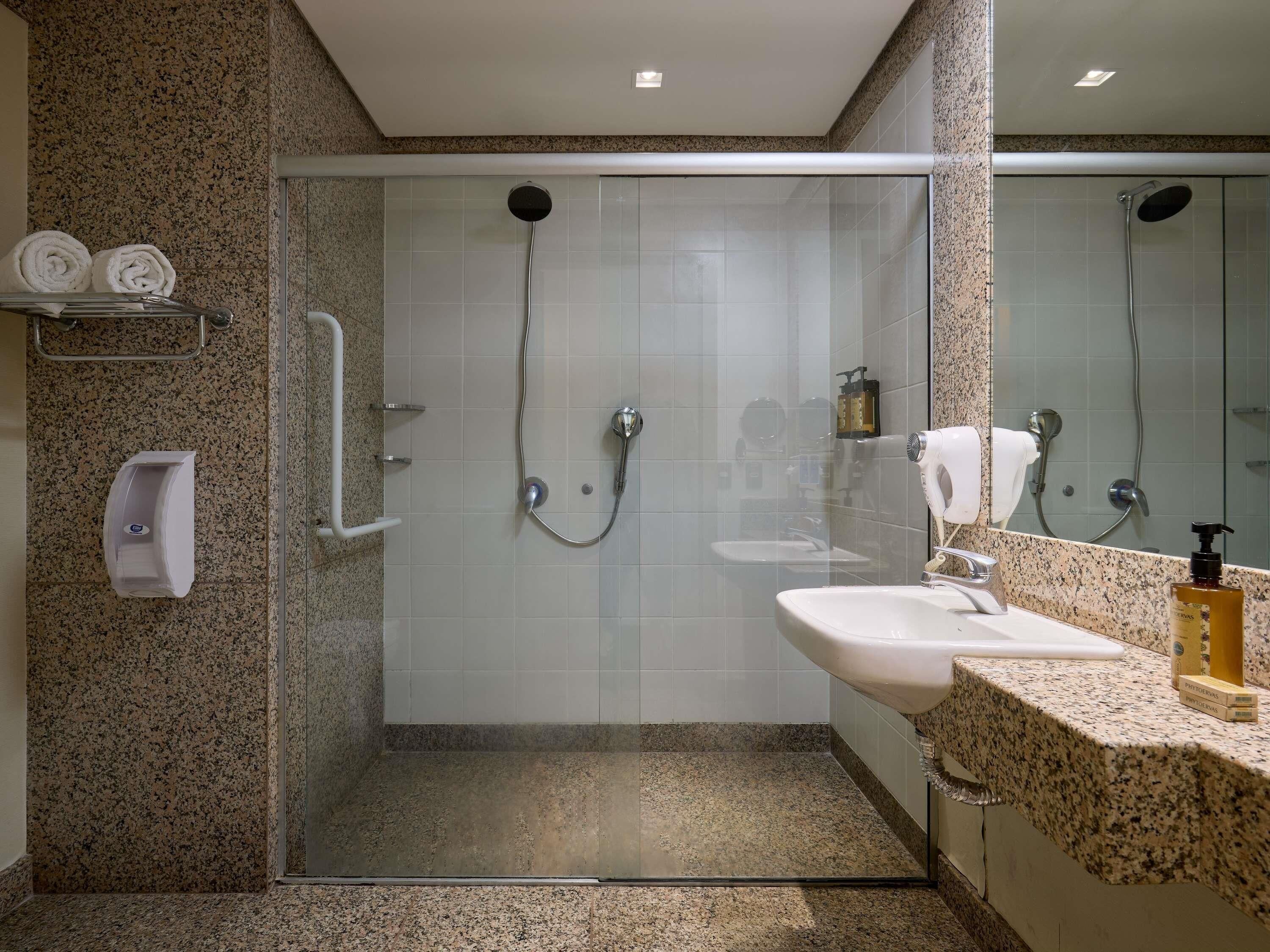 A modern bathroom with a glass-enclosed shower, a sink, and a hand dryer.