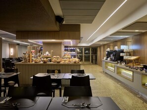 Un comedor moderno con barra de buffet, mesas con sillas y una estación de café.