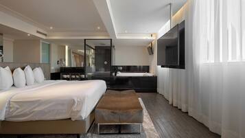 Quarto moderno com cama grande, televisão, banheiro e vista para a cidade.