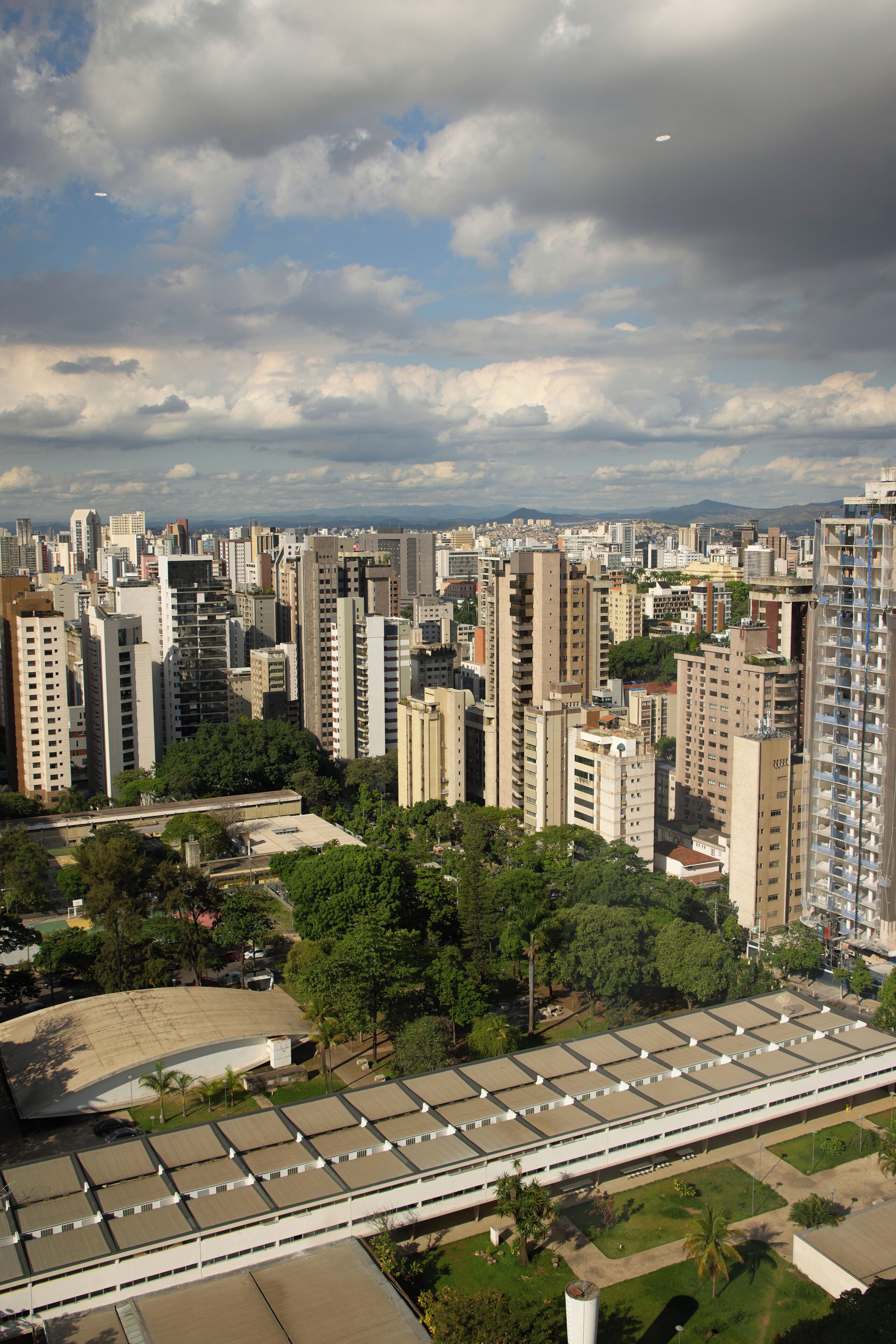 Zona urbana con edificios altos, un estacionamiento grande y áreas verdes.