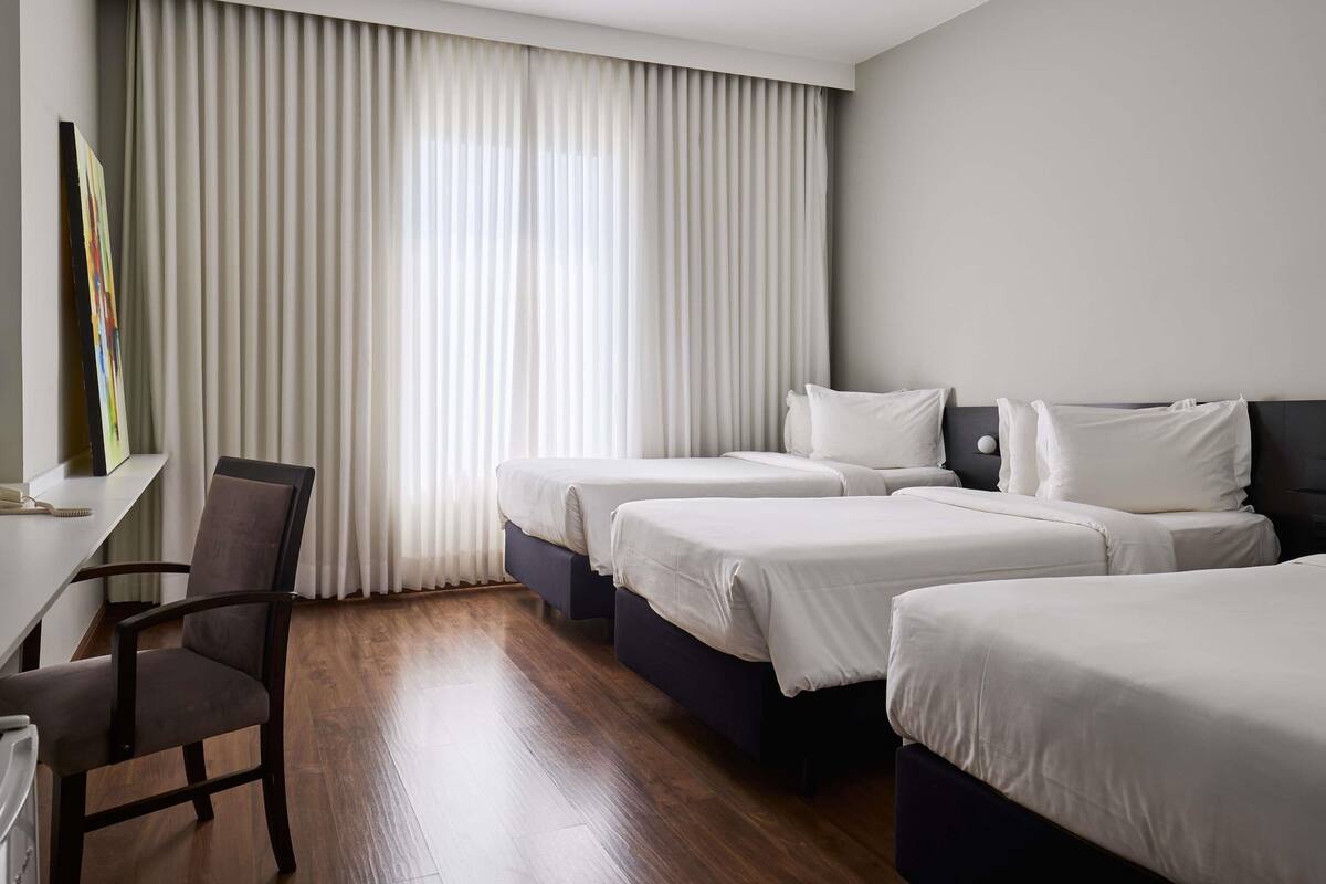 A hotel room with two beds, a desk, and a chair.