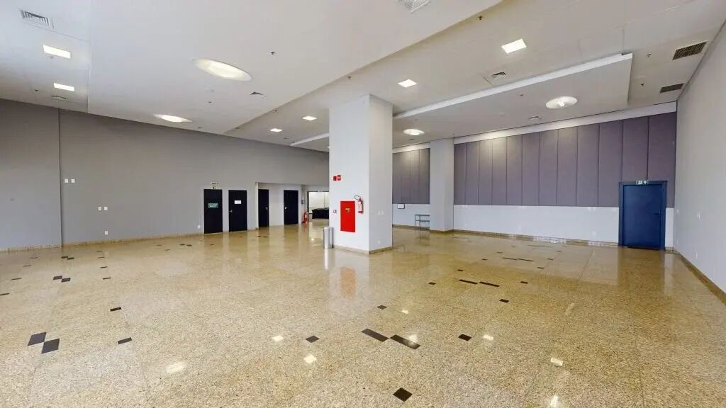 Een ruime hotellobby met een gepolijste vloer, een brandblusser en een blauwe deur.