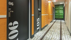 A hallway with doors numbered 106 and 105, leading to rooms. The floor has a patterned tile design. - ibis Styles La Rochelle Centre Vieux Port (La Rochelle)