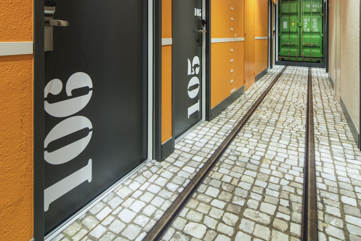 A hallway with doors numbered 106 and 105, leading to rooms. The floor has a patterned tile design.
