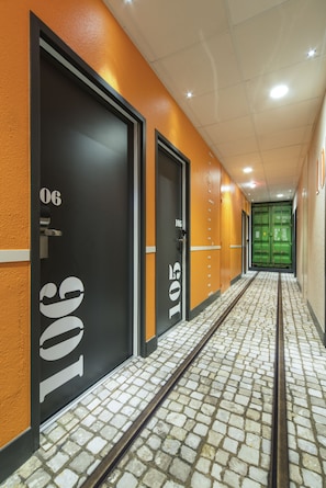 A hallway with doors numbered 106 and 105, leading to rooms. The floor has a patterned tile design. - ibis Styles La Rochelle Centre Vieux Port (La Rochelle)