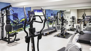 Uma academia com diversos equipamentos de exercício, incluindo esteiras, bicicletas ergométricas e máquinas de musculação.