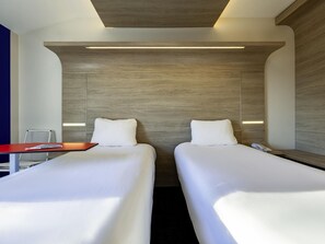 Habitació d'hotel amb dos llits, un escriptori i una cadira.