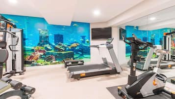 Ett gym med löpband, styrketräningsmaskiner och en väggmålning med undervattensmotiv.