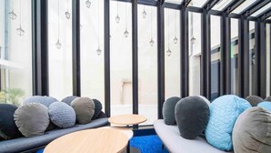 A modern interior with a seating area, large windows, and hanging lanterns. - ibis Styles La Rochelle Centre Vieux Port (La Rochelle)