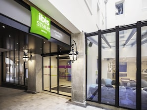 A hotel entrance with a green sign, glass doors, and a view into the interior. - ibis Styles La Rochelle Centre Vieux Port (La Rochelle)