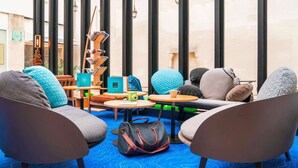 A modern lounge area with comfortable seating, a coffee table, and a bookshelf. - ibis Styles La Rochelle Centre Vieux Port (La Rochelle)