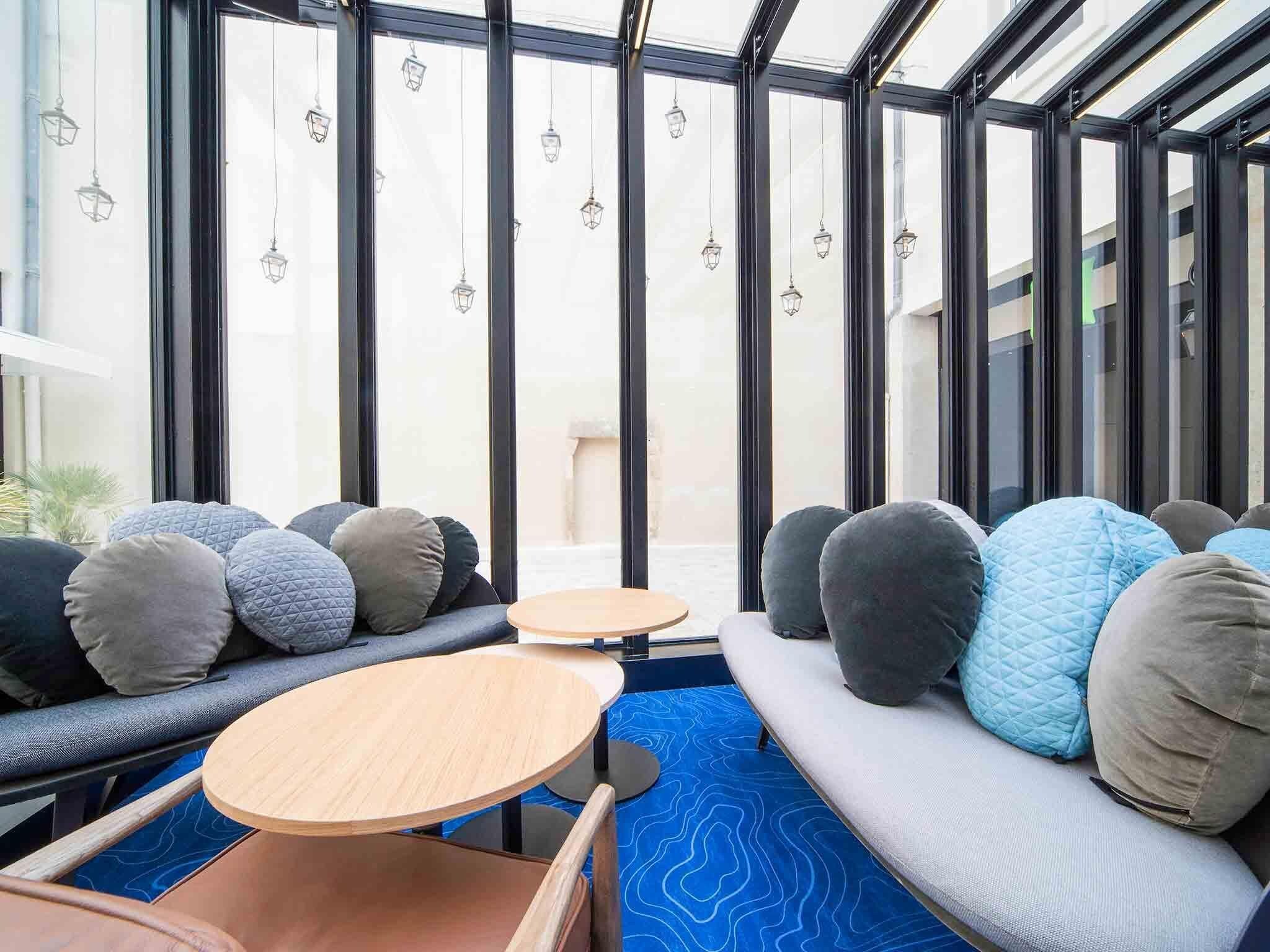 Un interior moderno con zona de estar, ventanas amplias y faroles colgantes.