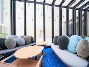 Un interior modern amb zona de seients, grans finestres i fanals penjants.