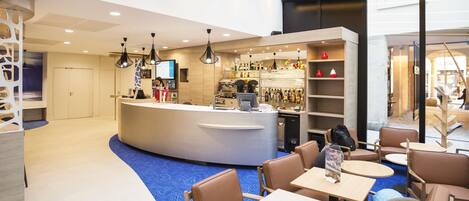 Un moderno vestíbulo de hotel con una recepción, zona de estar y bar.
