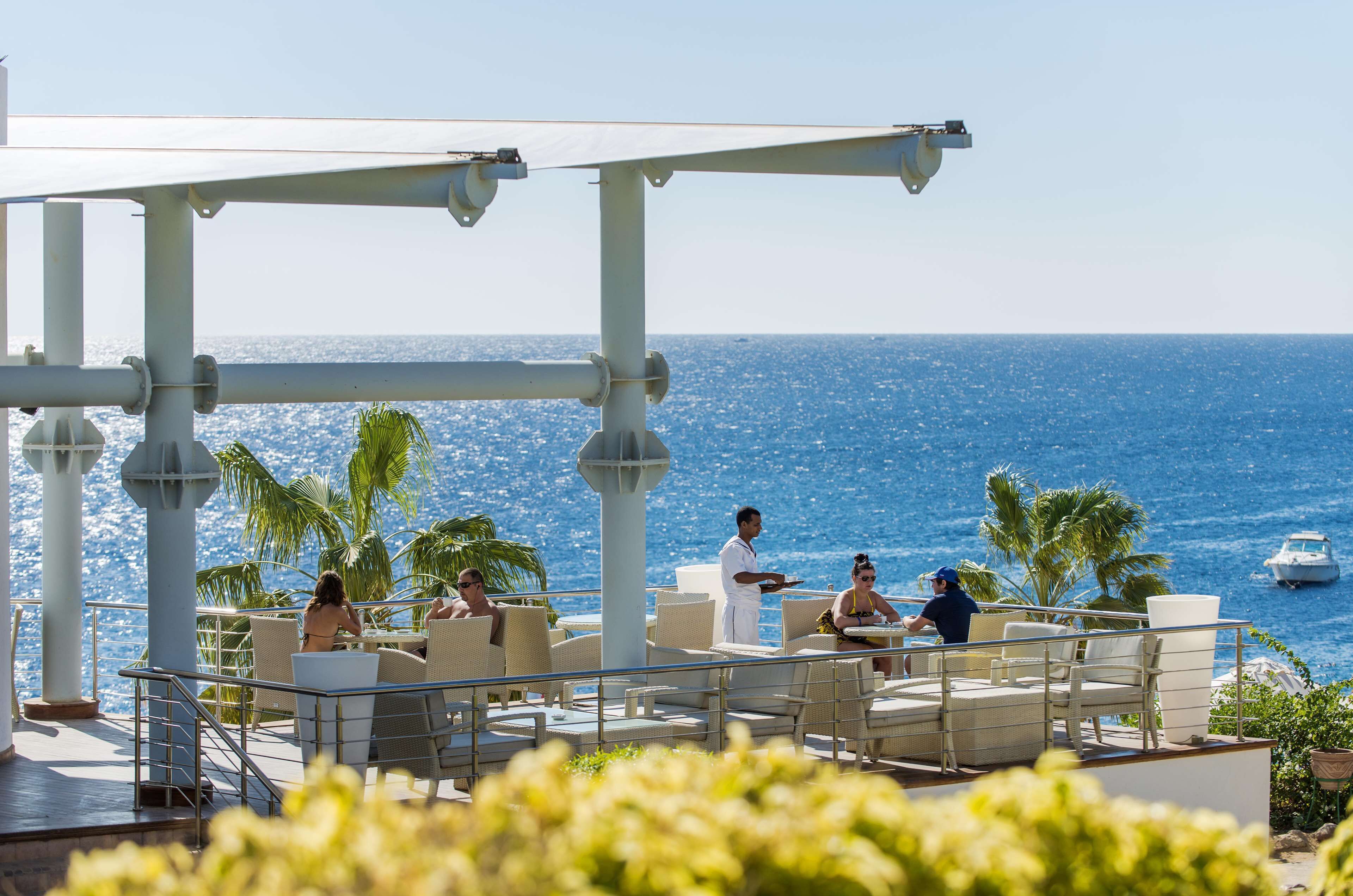 A rooftop bar with outdoor seating overlooking the ocean.